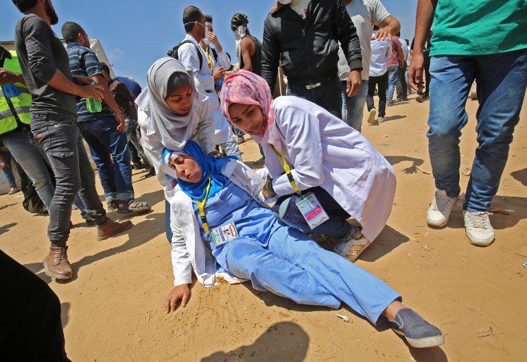 Médicos palestinos atienden a un colega herido durante enfrentamientos cerca de la frontera con Israel, al este de Khan Yunis en el sur de la Franja de Gaza el 15 de mayo de 2018