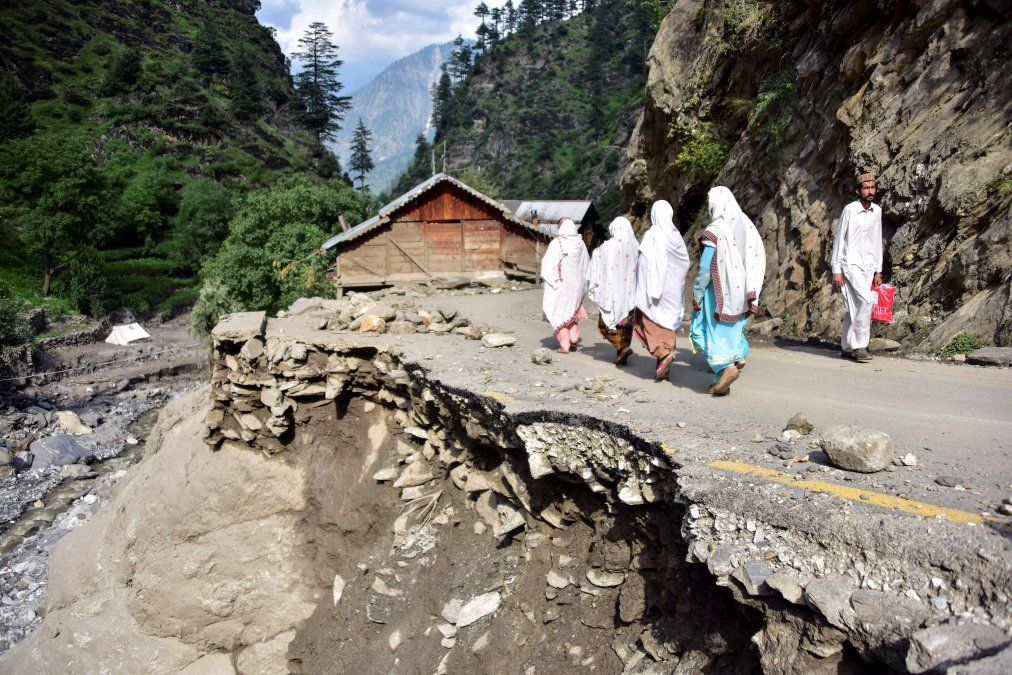 Afectados por las inundaciones en Pakistán caminan por una calle dañada en el valle de Laswa Afectados por las inundaciones en Pakistán caminan por una calle dañada en el valle de Laswa