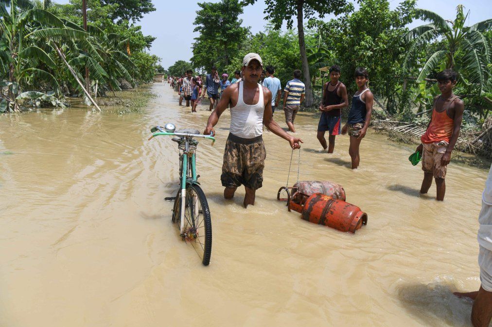 Un hombre camina por una calle inundada arrastrando su bicicleta y dos garrafas tras las fuertes lluvias monzónicas en India. Un hombre camina por una calle inundada arrastrando su bicicleta y dos garrafas tras las fuertes lluvias monzónicas en India.