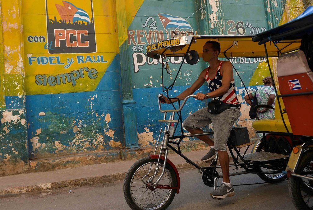 Un hombre pasa en bicicleta frente a un letrero que dice