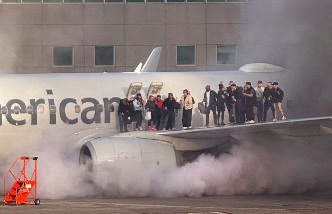 El avión con los pasajeros parados sobre una de la alas, esperando ser evacuados por personal de emergencia. Foto: AFP.