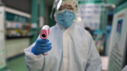 Un m&eacute;dico en China se prepara para tomar la temperatura