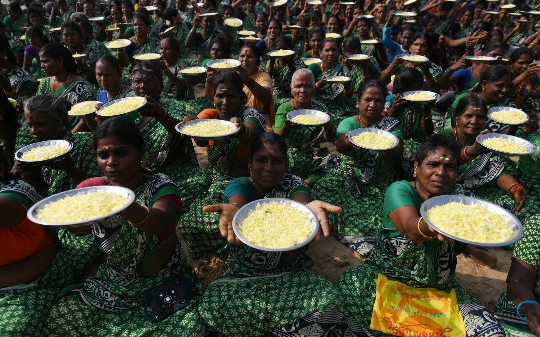 Mujeres indias posan mientras sostienen platos con pétalos de flores durante una ceremonia por las víctimas del tsunami de 2004