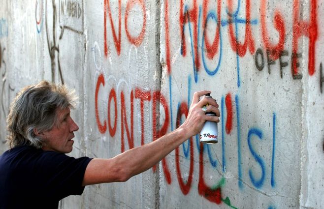 La leyenda del rock británico pinta un graffiti en el muro que rodea la ciudad Cisjordana de Belén el día antes de su concierto cerca de Tel Aviv, el 21 de junio de 2006. Waters realizó un dcumental junto con ONU sobre la difícil situación de los palestinos en 2009.&nbsp;