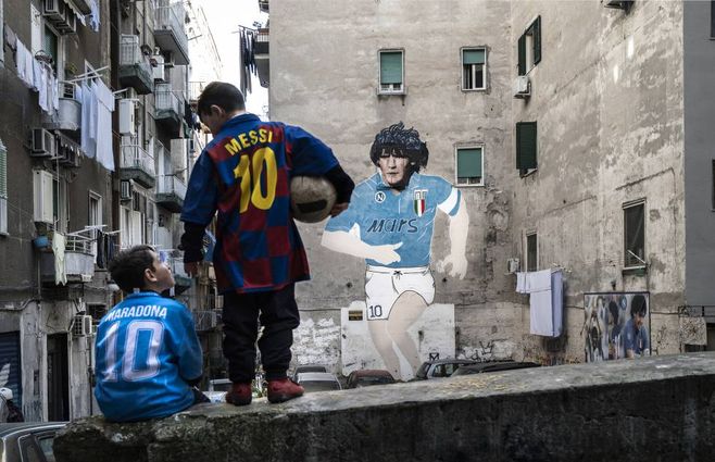 Dos ni&ntilde;os lucen las camisetas de Maradona y Messi en el barrio de Forcella (N&aacute;poles).