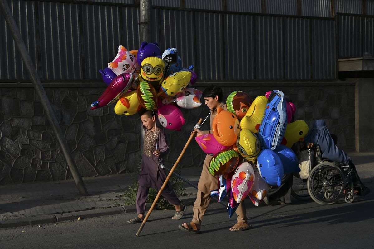 Vendedores de globos jóvenes caminan en busca de clientes por una calle de Kabul Afganistán.