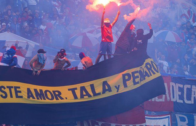 Foto: FocoUy. Hinchas de Nacional usan pirotecnia y muestran bandera rival durante el clásico del 6 de julio de 2025.