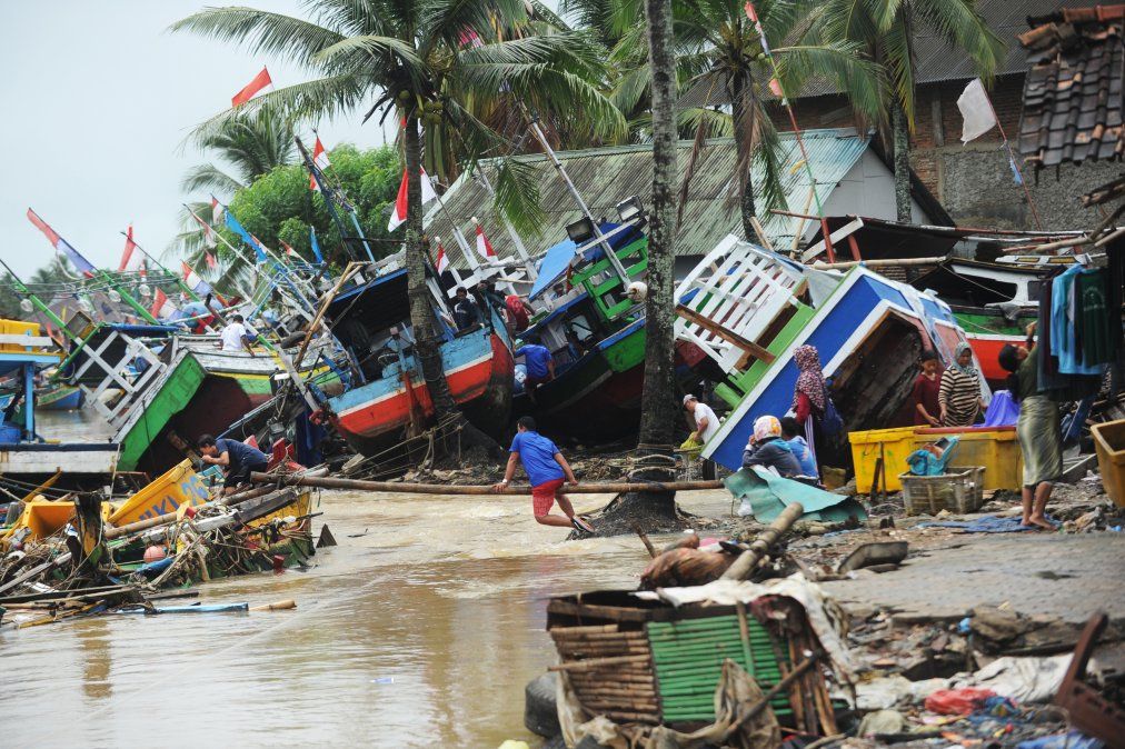 Los pescadores atienden a sus barcos tradicionales que se dañaron después de ser golpeados por un tsunami en la aldea de Teluk, en Indonesia