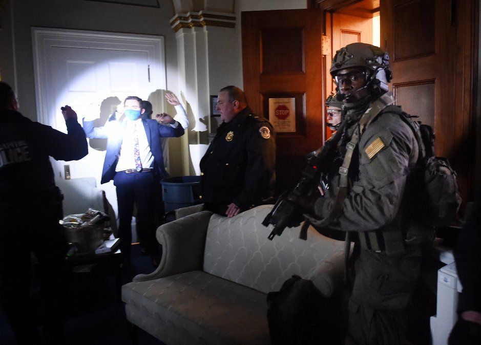 Personal del Congreso levanta las manos mientras los equipos Swat de la Policía del Capitolio revisan a todos en la sala mientras aseguran el piso.