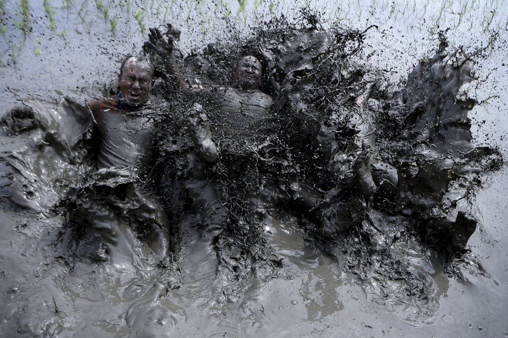 Agricultores cubiertos de barro juegan en un campo durante el Día Nacional del Arroz, que marca el inicio de la temporada anual de siembra, en la aldea de Tokha, en las afueras de Katmandú.
