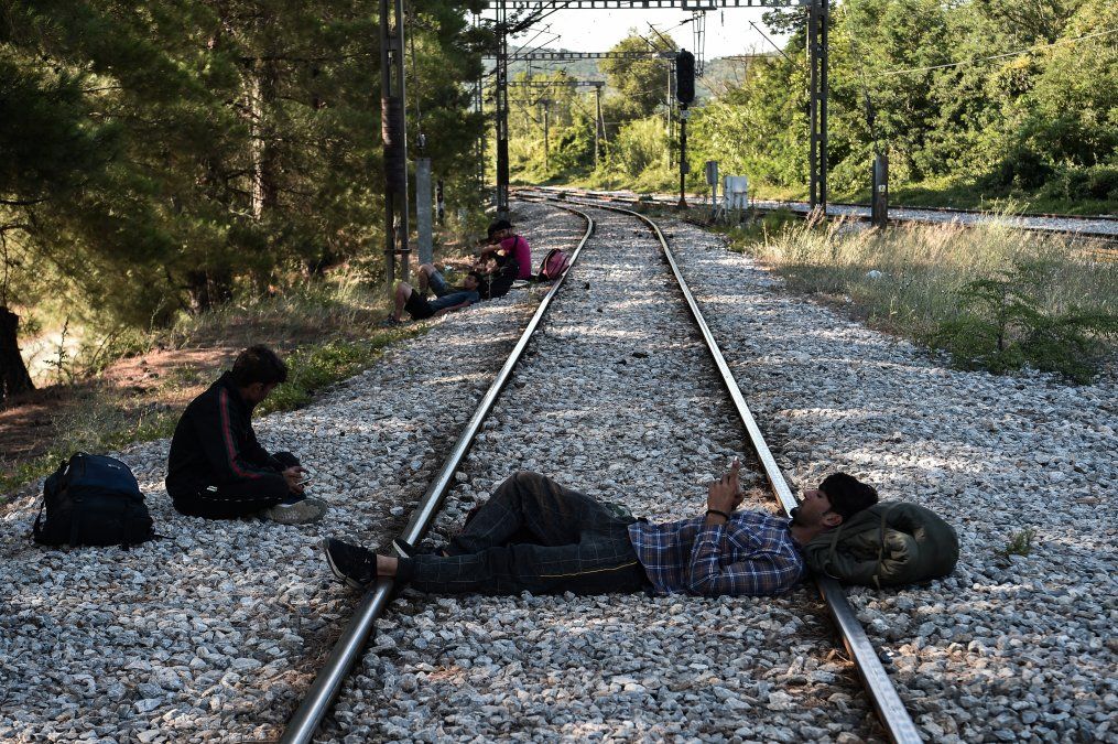 Migrantes descansan sobre la v&iacute;a del tren cerca de la estaci&oacute;n de Idomeni, en la frontera entre Grecia y Macedonia del Norte