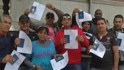 cubanos festejan la obtencion del papel que les permite regularizar su situacion