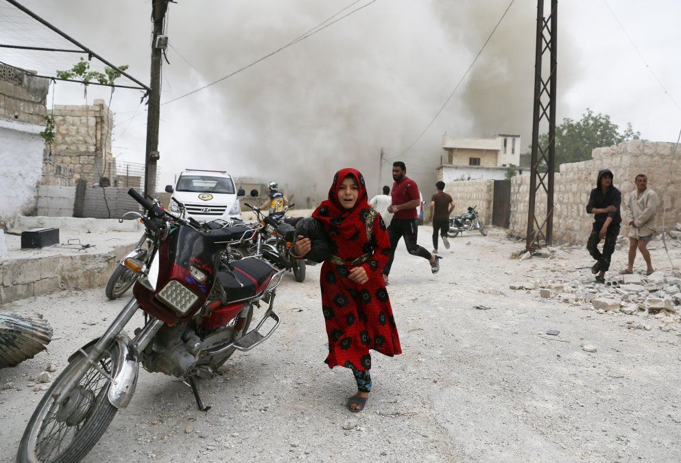 Los sirios corren a esconderse durante un ataque aéreo de las fuerzas pro régimen en la ciudad de Kfar Ruma