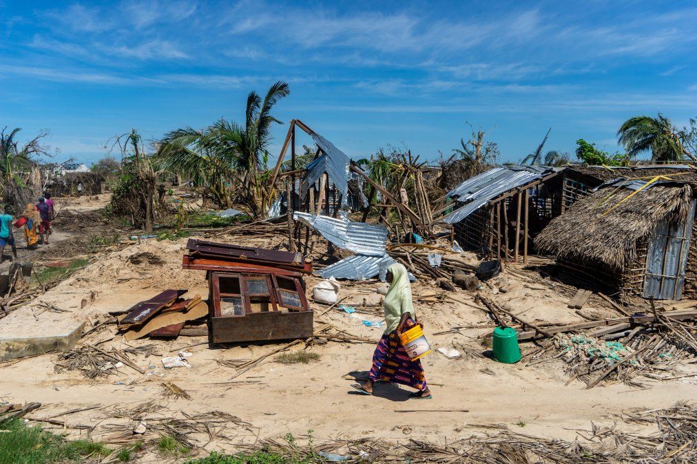 Una mujer camina pasando por casas destruidas rumbo a un centro de distribucuión de ayuda en la villa costera de Guludo&nbsp; en Mozambique