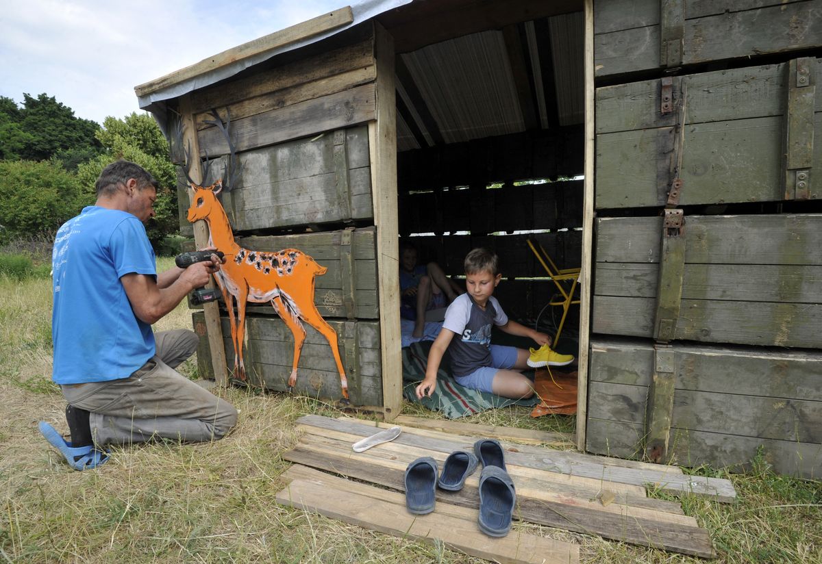Un hombre decora una cabaña para niños hecha con cajas de municiones usadas en el pueblo de Novoselova, en las afueras de Chernigiv, Ucrania. Foto: AFP.