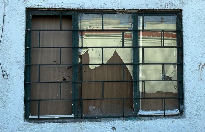 Foto: Subrayado. Impactos de bala en la madera que cubre la ventana y en la fachada de hormigón.