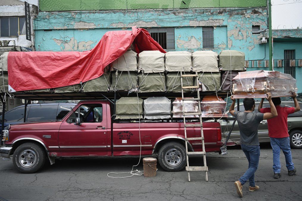 Trabajadores descargan ataúdes de un camión frente a una funeraria ubicada frente al Hospital General en la Ciudad de México, en medio de la pandemia del coronavirus COVID-19.