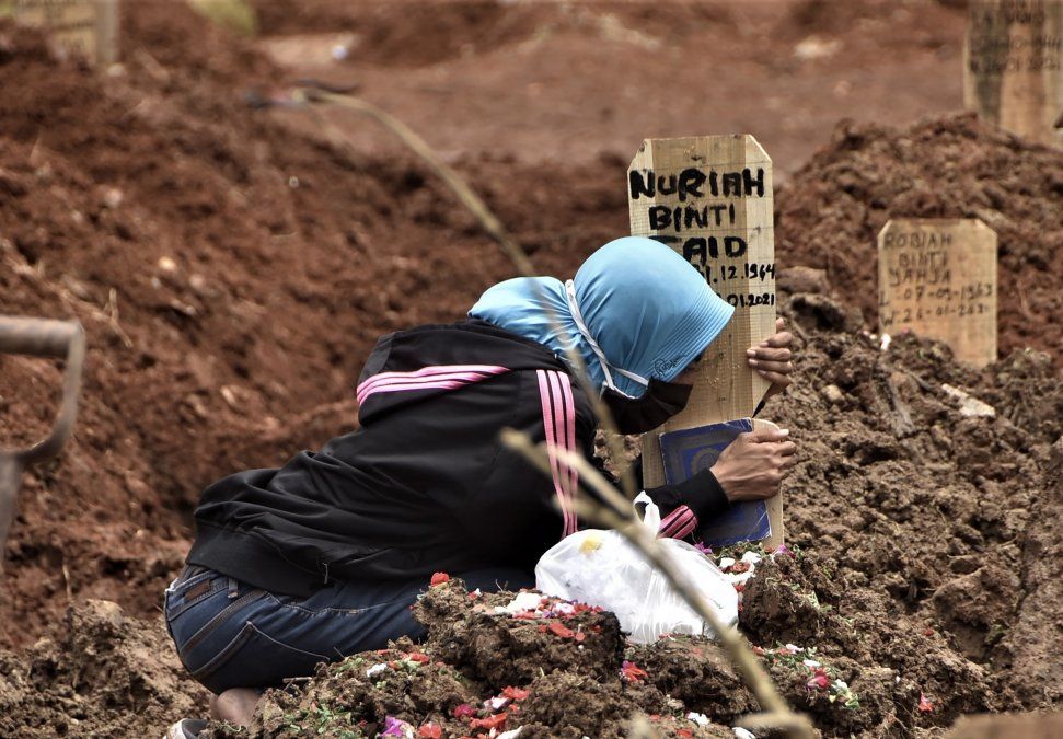 Una mujer se aferra a la tumba de un ser querido que murió por Covid en el cementerio de Bekasi, Indonesia