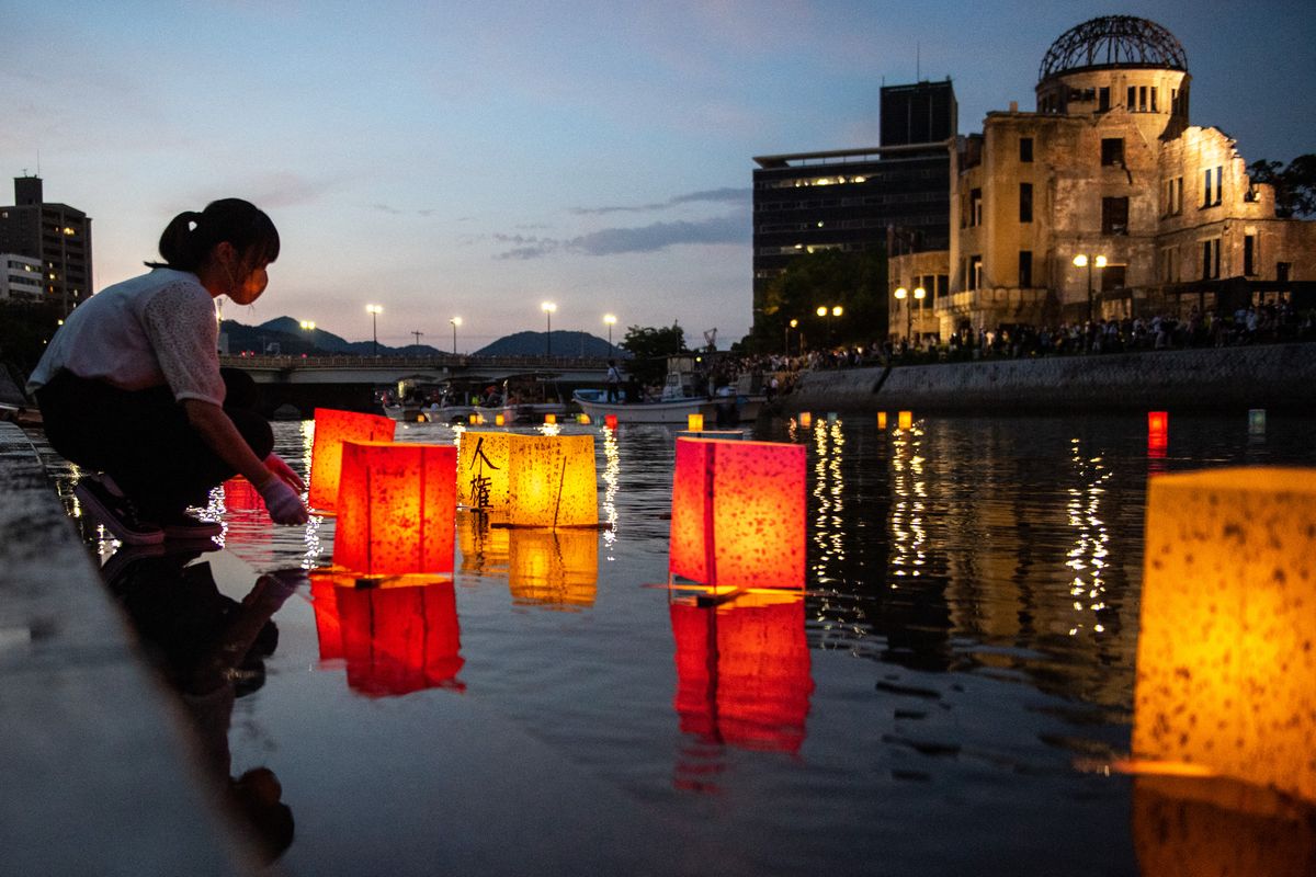 Personas lanzan linternas de papel en el río Motoyasu junto al Salón de Promoción Industrial de la Prefectura de Hiroshima, comúnmente conocido como el domo de la bomba atómica, para conmemorar el 77 aniversario del primer ataque con bomba atómica del mundo en Hiroshima el 6 de agosto de 2022. Foto: AFP.