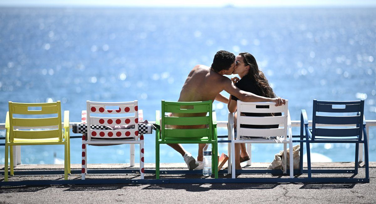 Una pareja se besa&nbsp;mientras están sentados en sillas pintadas con las camisetas de los líderes de la 107 edición de la carrera ciclista Tour De France, en el promenade des Anglais de la ciudad de Niza en la Riviera francesa.