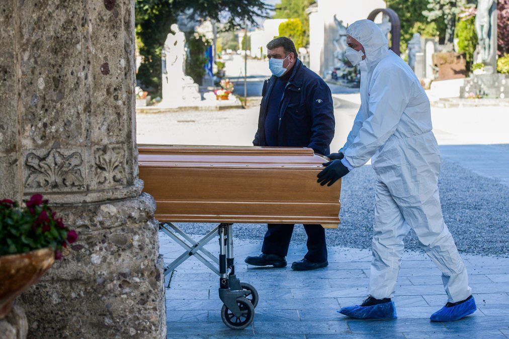 Trabajadores de una funeraria con m&aacute;scara facial y un ata&uacute;d ingresan al cementerio de B&eacute;rgamo, en Lombard&iacute;a