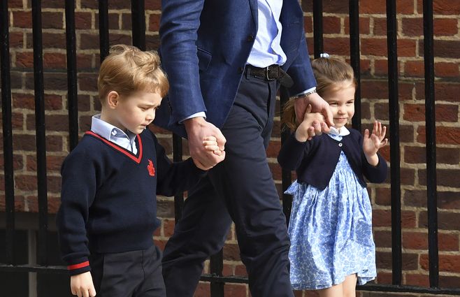 Princesa Charlotte de Cambridge (D) saluda a los medios mientras camina con su hermano, el Príncipe George de Cambridge (I) de la mano de su padre, el Príncipe William, Duque de Cambridge, rumbo a Lindo Wing del Hospital St Mary en Londres, el 23 de abril, a visitar a Catherine (Kate), duquesa de Cambridge, y su hermano recién nacido, tercer hijo de William y Kate.