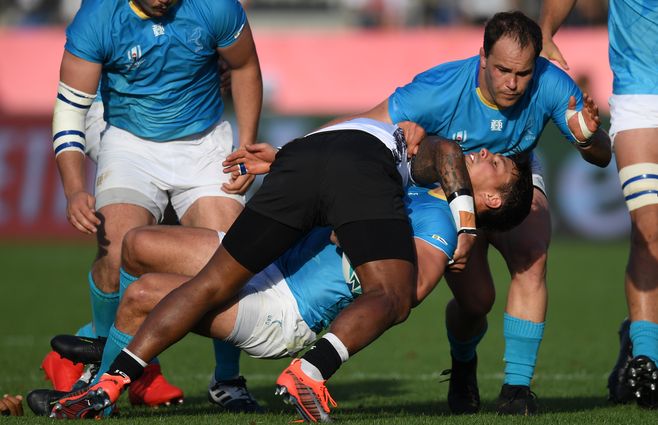 El ala uruguaya Nicolas Freitas (2R) es abordado por el medio scrum de Fiji Nikola Matawalu (C) durante el Mundial de Rugby de Japón 2019.