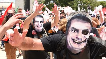 Manifestantes de movimientos sociales con máscaras que representan al presidente Jair Bolsonaro protestan contra las políticas gubernamentales frente al Palacio Planalto en Brasilia, el 20 de octubre de 2021