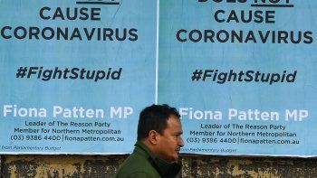 El peat&oacute;n pasa junto a los carteles de anuncios de servicio p&uacute;blico, negando una conspiraci&oacute;n de que la tecnolog&iacute;a de telecomunicaciones 5G causa el coronavirus. La campa&ntilde;la se desarrolla bajo el hashtag #Est&uacute;pidaCausa en Melbourne, 24 de junio de 2020. William WEST / AFP