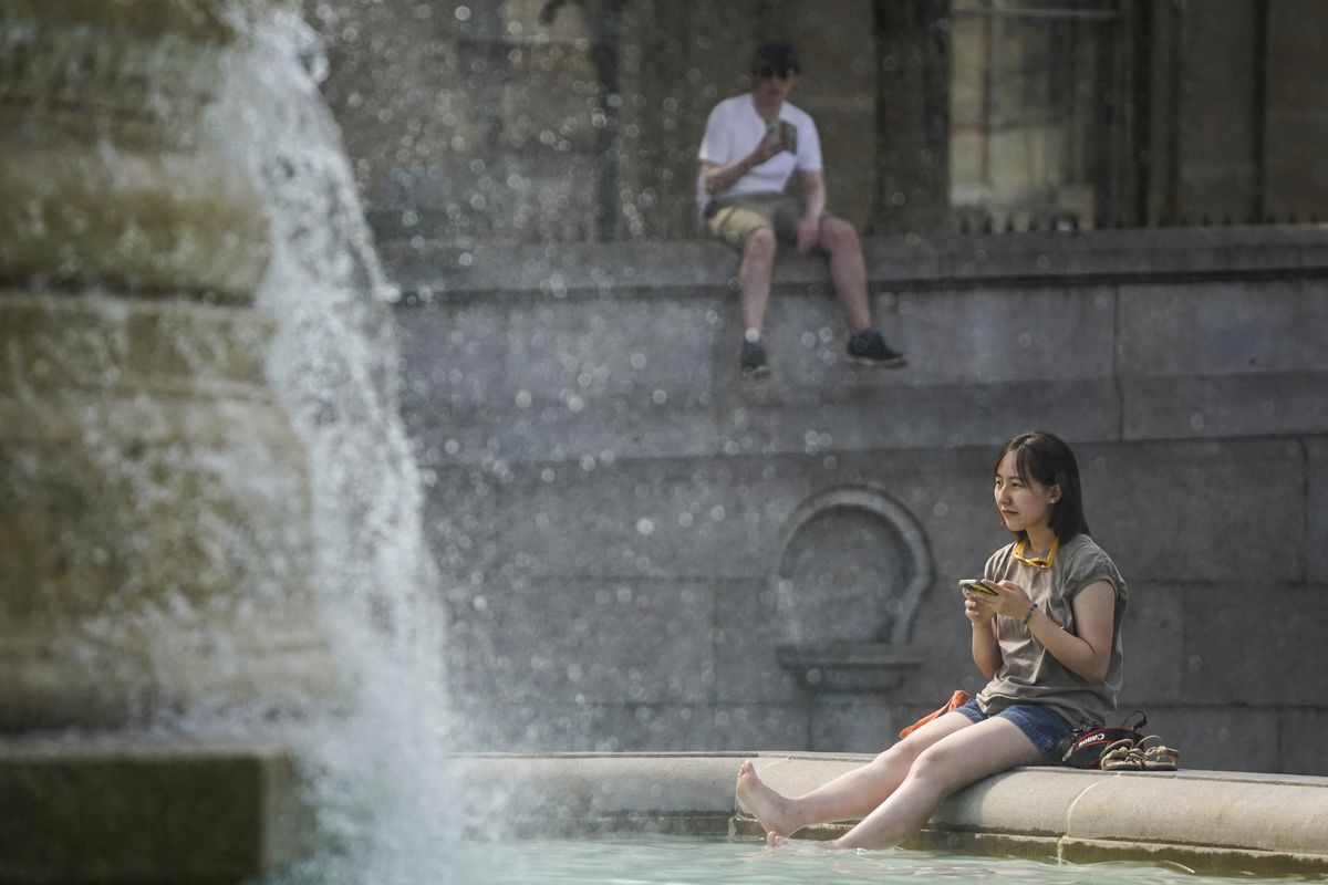 Una mujer se refresca sumergiendo sus pies en la fuente de Trafalgar Square, en el centro de Londres, el 18 de julio de 2022 mientras el país experimenta una ola de calor extremo. Foto: AFP