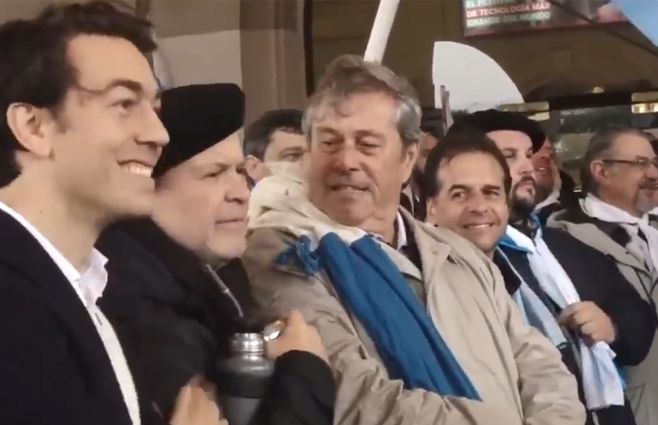 Iturralde se sale del protocolo y da un paso adelante interponiéndose entre Sartori y los otros precabdidatos presentes, Antía y Lacalle Pou. Sartori sonríe y le da una palmada al diputado