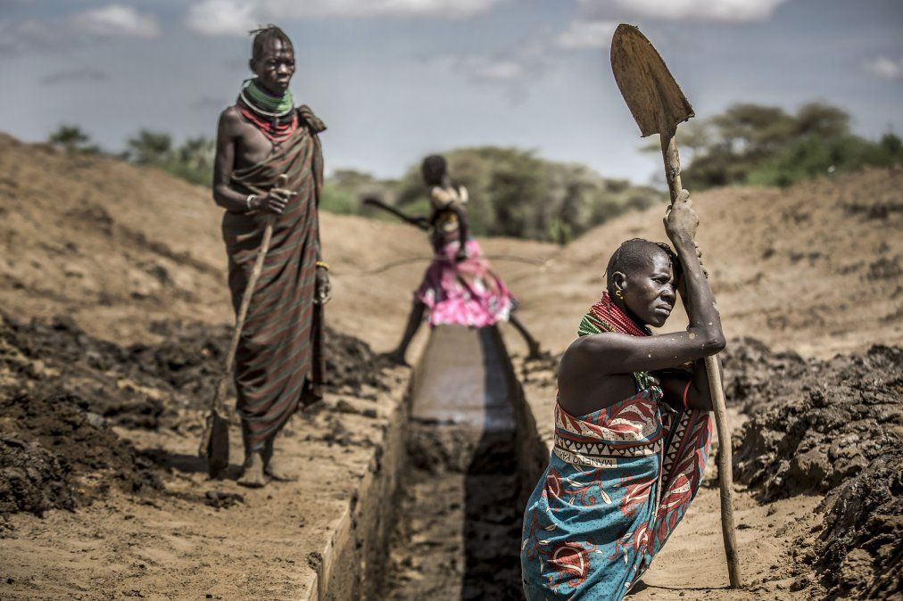 Los miembros de la comunidad de Turkana trabajan para desbloquear un canal de riego para proporcionar agua a sus cultivos de sorgo en un área árida y seca en Nanyee.