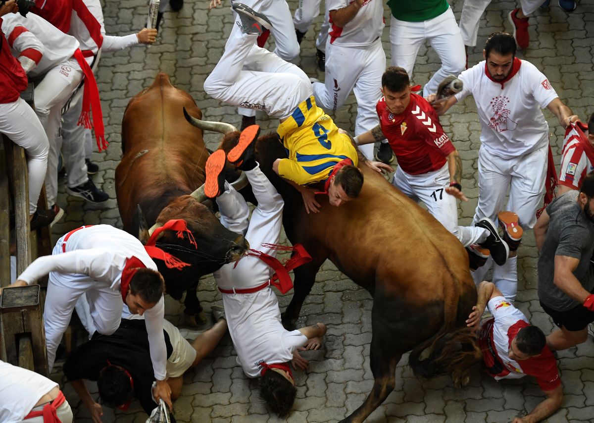 Un participante es corneado por un toro durante el quinto encierro (corrida de toros) de las fiestas de San Fermín en Pamplona, norte de España, el 11 de julio de 2022.&nbsp; Foto: AFP