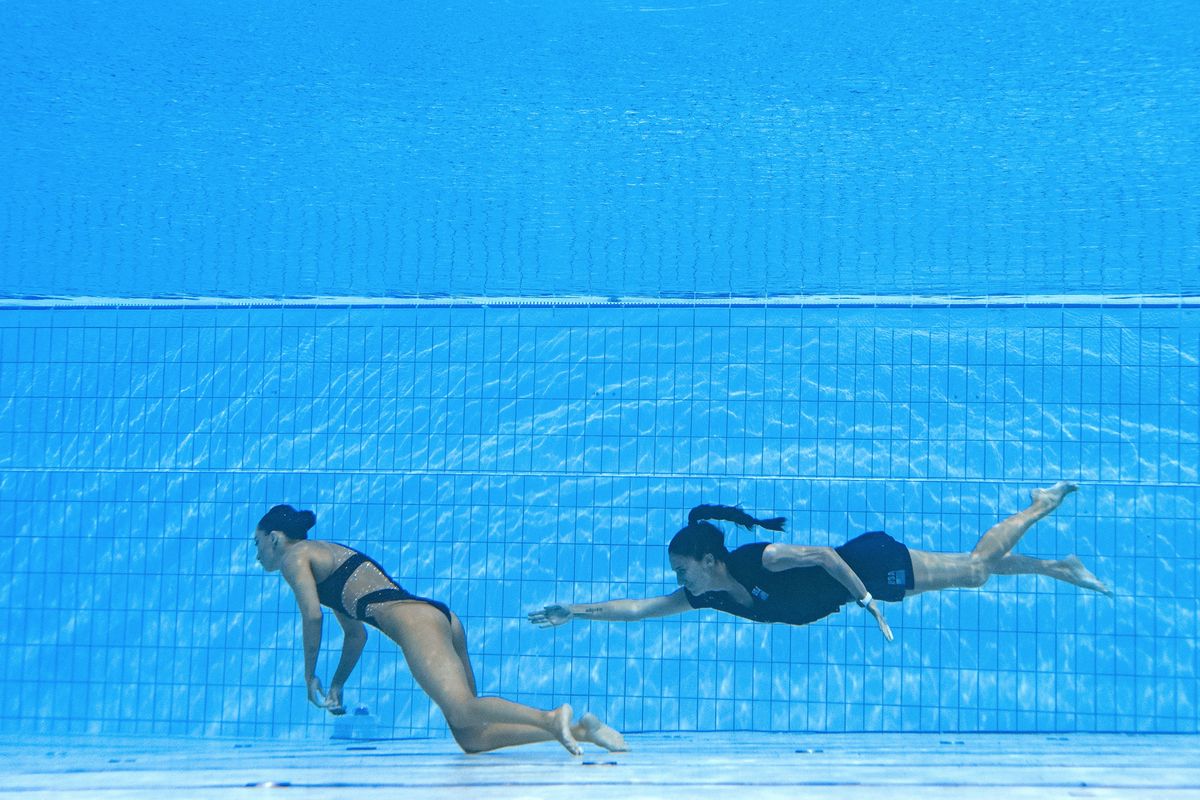 La entrenadora de EE. UU., Andrea Fuentes (D), nada para salvar a Anita Alvarez (L), de EE. UU., del fondo de la piscina durante un incidente en la final femenina de natación artística libre en solitario, durante el Campeonato Mundial Acuático de Budapest 2022. Foto: AFP.