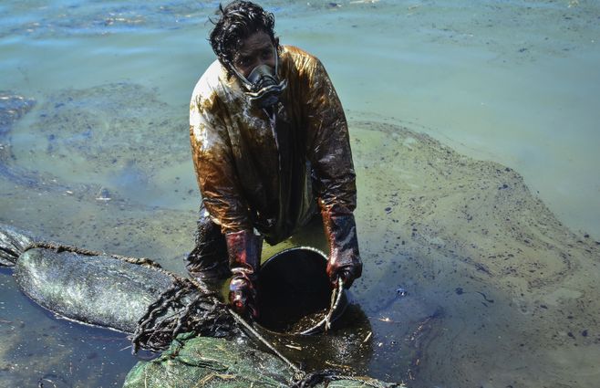 Un hombre extrae aceite derramado del buqye MV Wakashio que encall&oacute; cerca de Blue Bay frente a la costa sureste de Mauricio