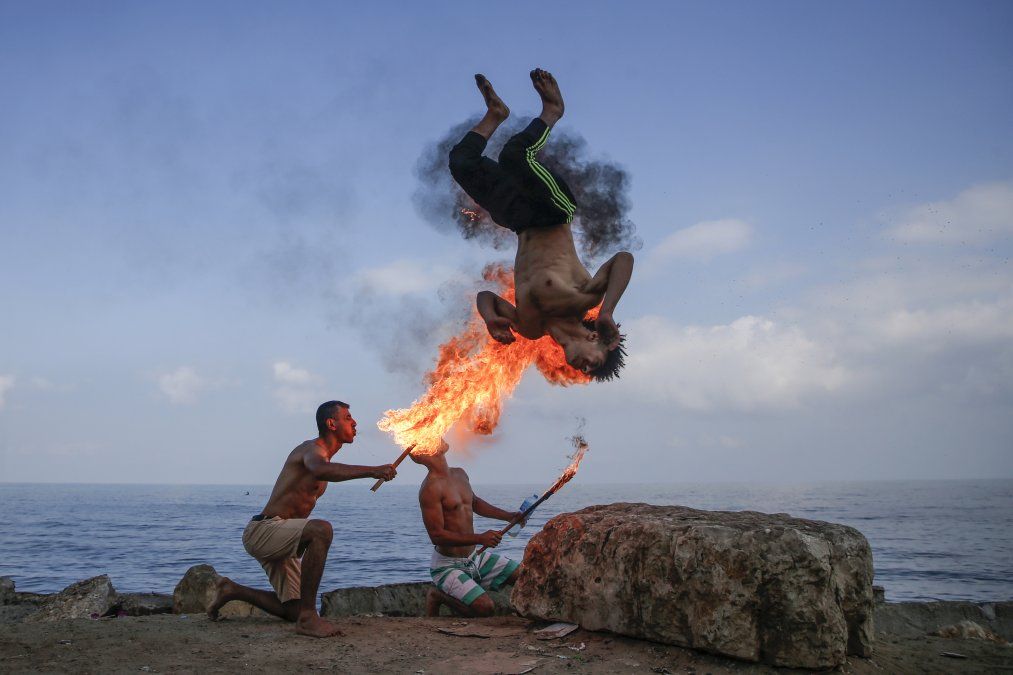 Un hombre palestino hace una performance con fuego en la playa como entretenimiento para los niños en Gaza