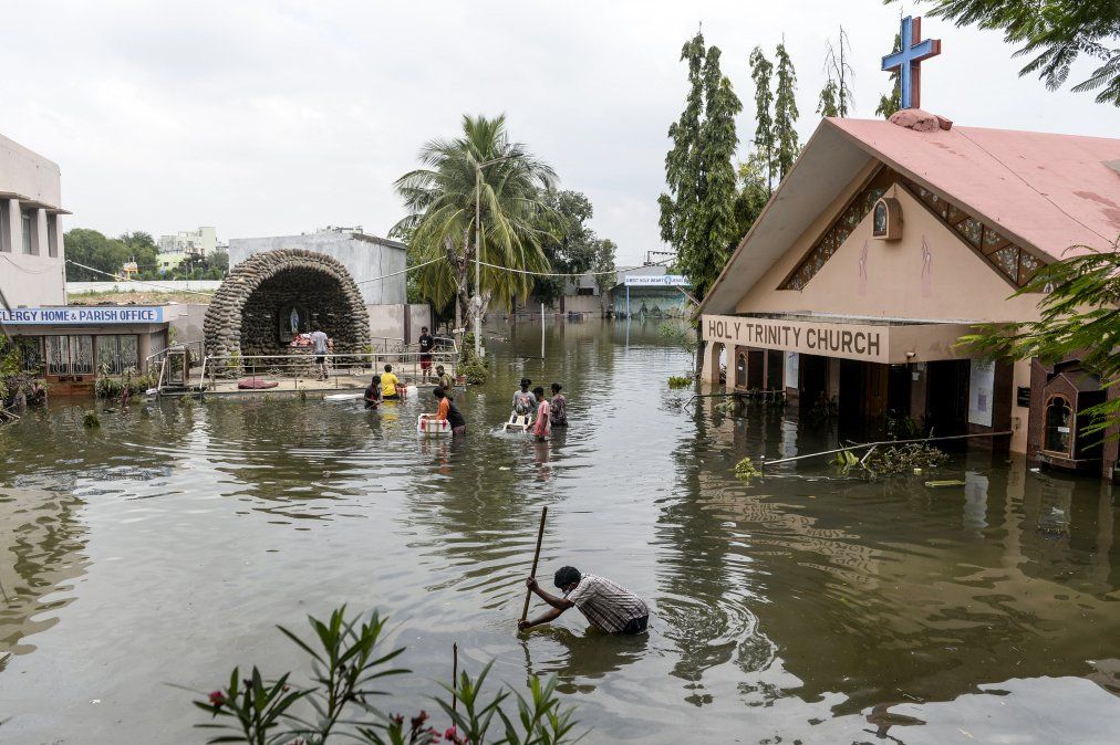 Fieles transportan materiales de la Iglesia Santa Trinidad tras las fuertes lluvias, en India