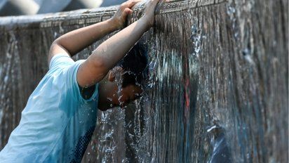 (AFP) Niño se moja en una fuente de Moscú, 13 de julio.