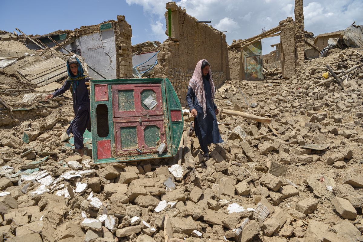 Hombres afganos buscan sus pertenencias entre las ruinas de una casa dañada por un terremoto en el distrito de Bermal, provincia de Paktika, el 23 de junio de 2022. El terremoto mató al menos a 1.000 personas y dejó a miles más sin hogar. Foto: AFP.