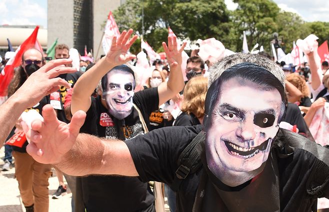 Manifestantes de movimientos sociales con máscaras que representan al presidente Jair Bolsonaro protestan contra las políticas gubernamentales frente al Palacio Planalto en Brasilia, el 20 de octubre de 2021