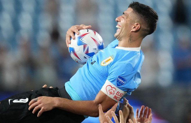 Luis Suárez cuando es tirado hacia arriba por sus compañeros, con la pelota debajo del brazo. AFP