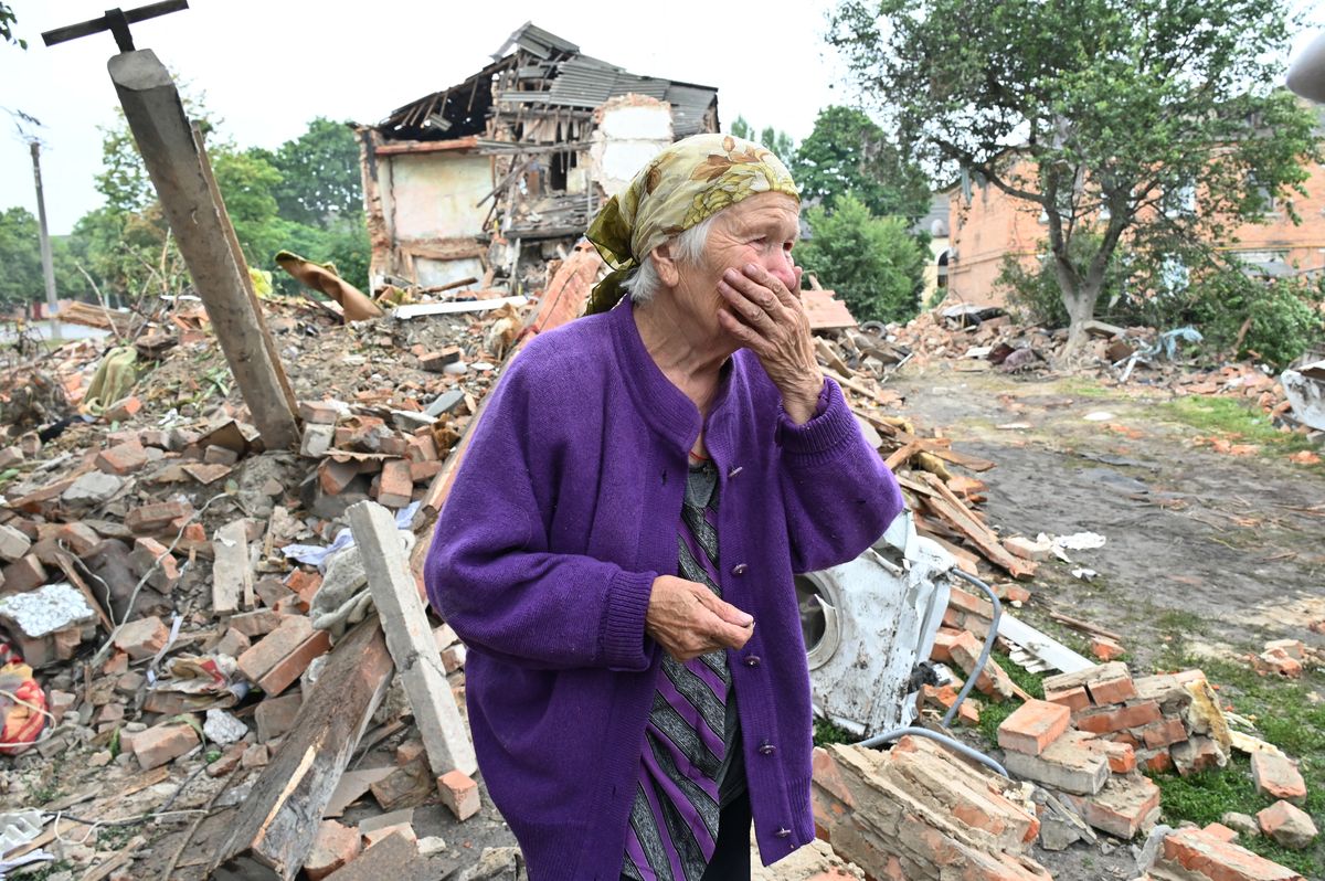 Una residente local, Raisa Kuval, de 82 años, fotografiada junto a un edificio parcialmente destruido después de un bombardeo en la ciudad de Chuguiv, al este de Kharkiv, el 16 de julio de 2022. Foto: AFP