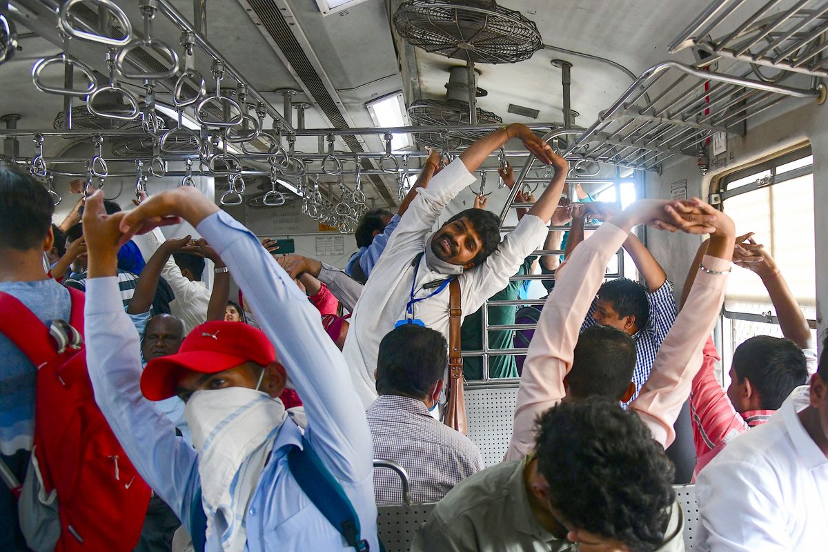 Un instructor (C) guía a los pasajeros con ejercicios de yoga mientras viajan en un tren local para celebrar el Día Internacional del Yoga en Mumbai el 21 de junio de 2022. Foto: AFP.&nbsp;