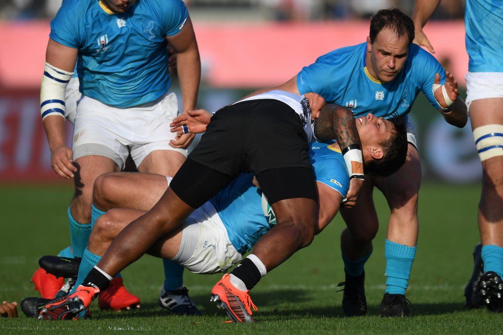 El ala uruguaya Nicolas Freitas (2R) es abordado por el medio scrum de Fiji Nikola Matawalu (C) durante el Mundial de Rugby de Japón 2019.