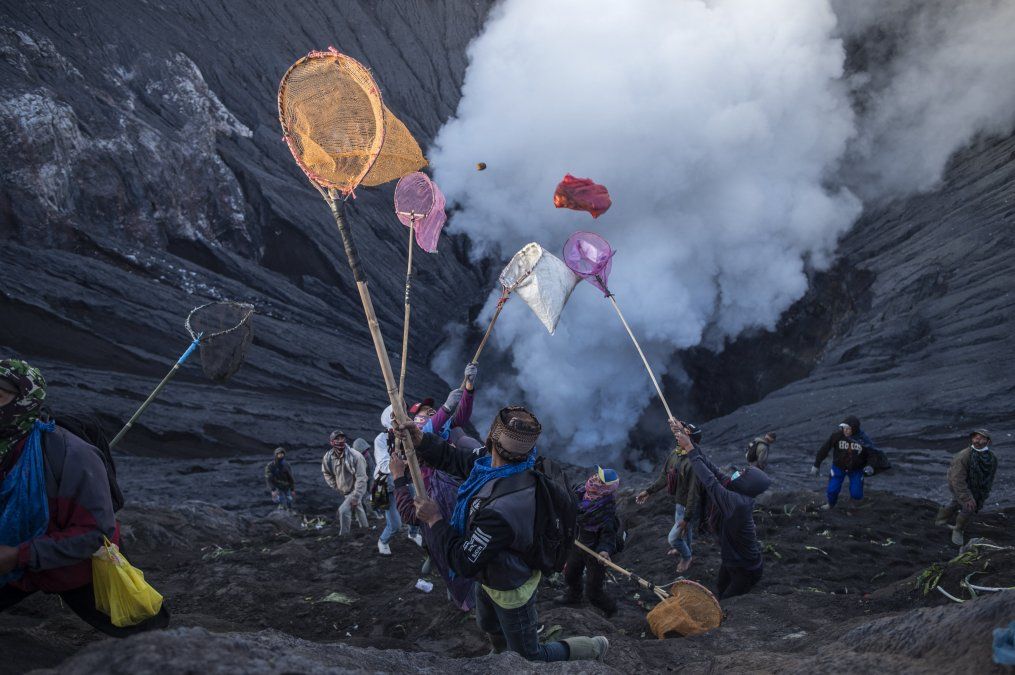 La gente intenta atrapar las ofrendas lanzadas por la gente de la tribu Tengger desde la cima del volcán activo Monte Bromo en Probolinggo, provincia de Java Oriental