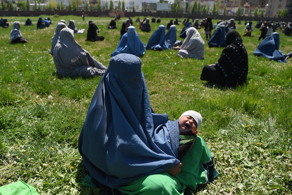 Una mujer que lleva un burka sostiene a su hijo mientras espera recibir trigo gratis del comit&eacute; de emergencia en Kabul