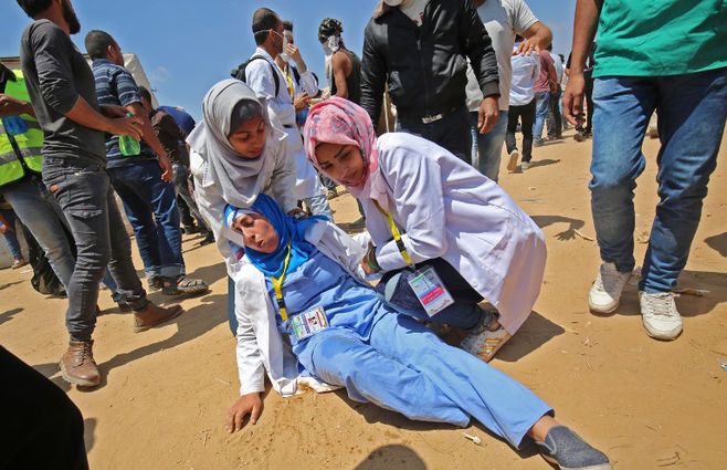 Médicos palestinos atienden a un colega herido durante enfrentamientos cerca de la frontera con Israel, al este de Khan Yunis en el sur de la Franja de Gaza el 15 de mayo de 2018