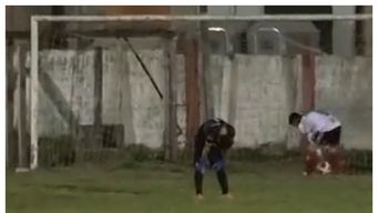 El golero mirando al suelo, manos en la rodilla, totalmente desconsolado. Atrás un delantero rival la va a buscar adentro del arco.&nbsp;