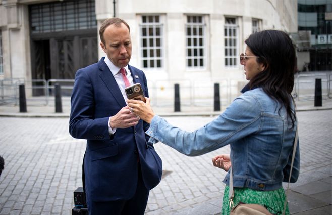 El ministro británico de Salud Matt Hancock mira el teléfono de su asistente Gina Coladangelo (AFP).