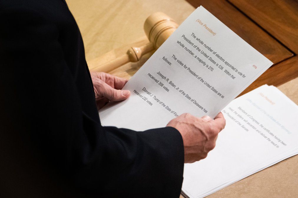 El vicepresidente Mike Pence, lee un papel con los recuentos de votos electorales finales que declaran a Biden como el próximo presidente, el 7 de enero.